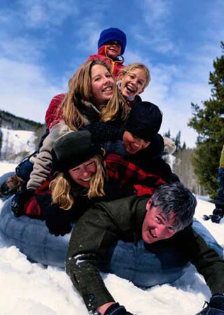 Family going downhill snow tubing in a pile.