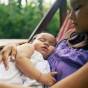 Young girl cradling sleeping infant.