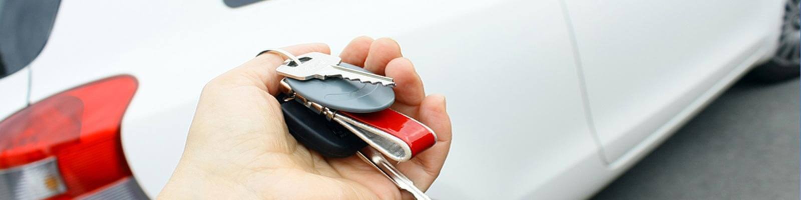 Close-up of Palm with car keys and white car in background.