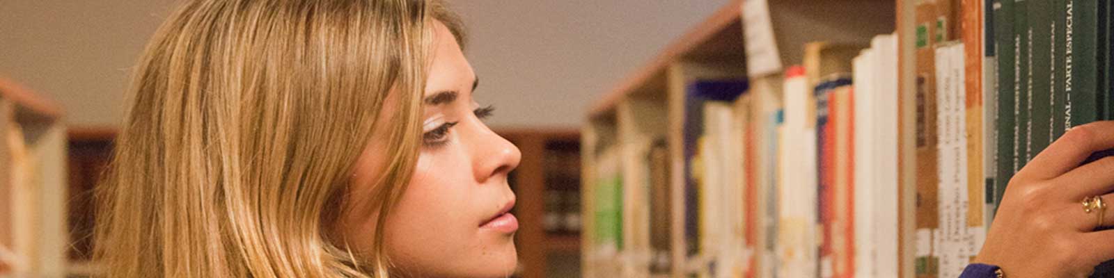 Young Girl perusing books on a bookshelf.