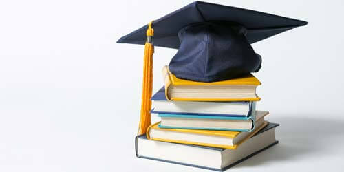 Mortarboard Cap on a pile of textbooks.