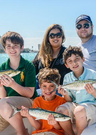 Family picture with 3 sons having caught fish.