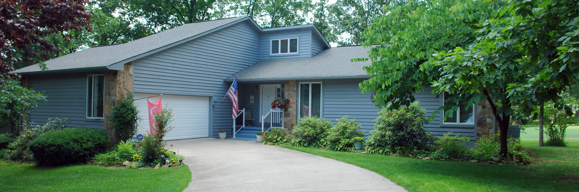 A beautiful blue slate colored home in Glade, Tennessee surrounded by green trees and lush grass.