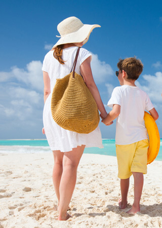 Mother and Son walking hand in hand in the sand.