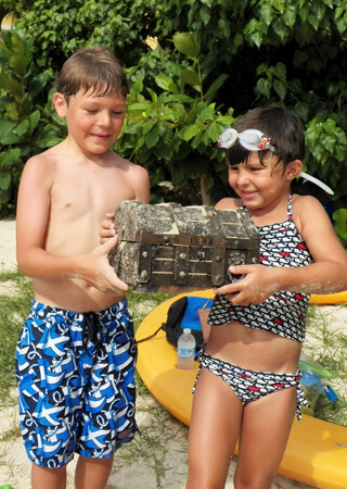 Boy and girl in bathing suits with treasure chest.